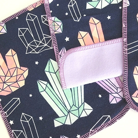 A close-up of the stitching, the cloth wipes are a rounded rectangle shape and stitched with a lilac purple thread.