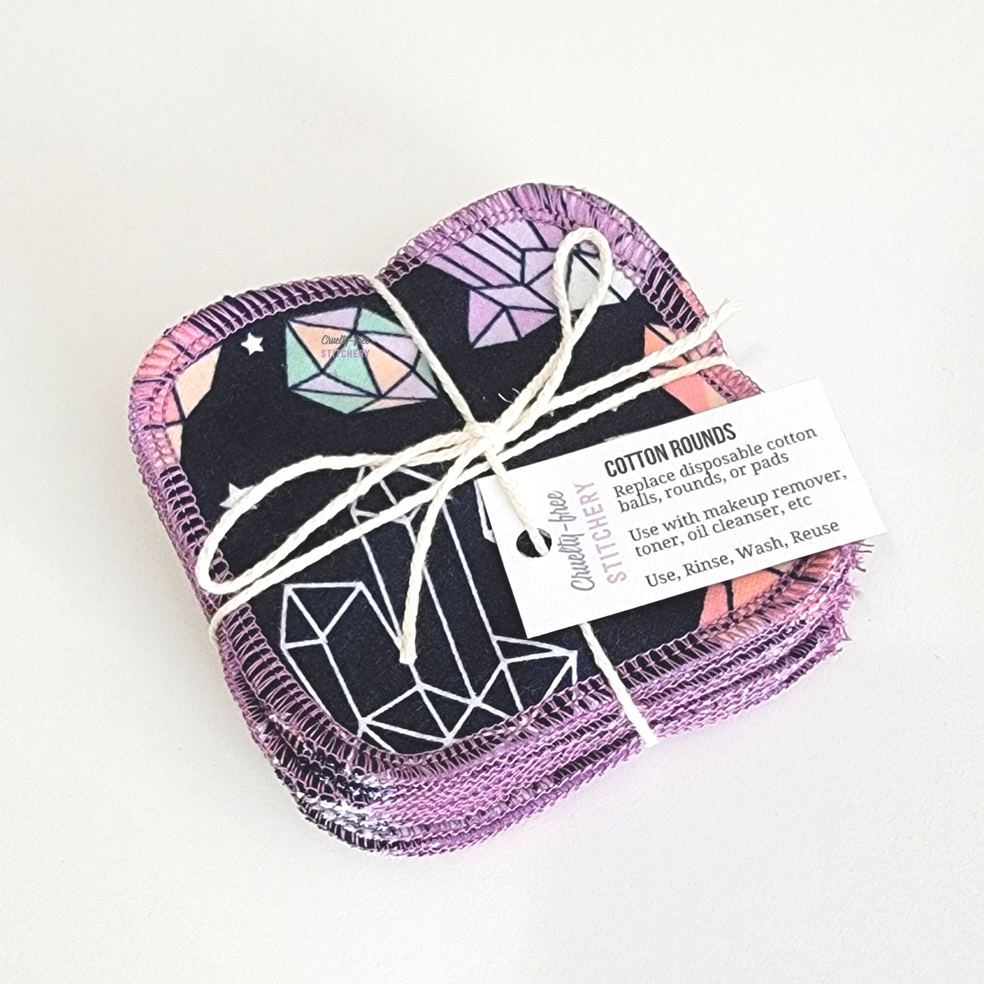 A bundled pack of crystals print reusable cotton rounds, tied with a cotton string and a small paper tag.