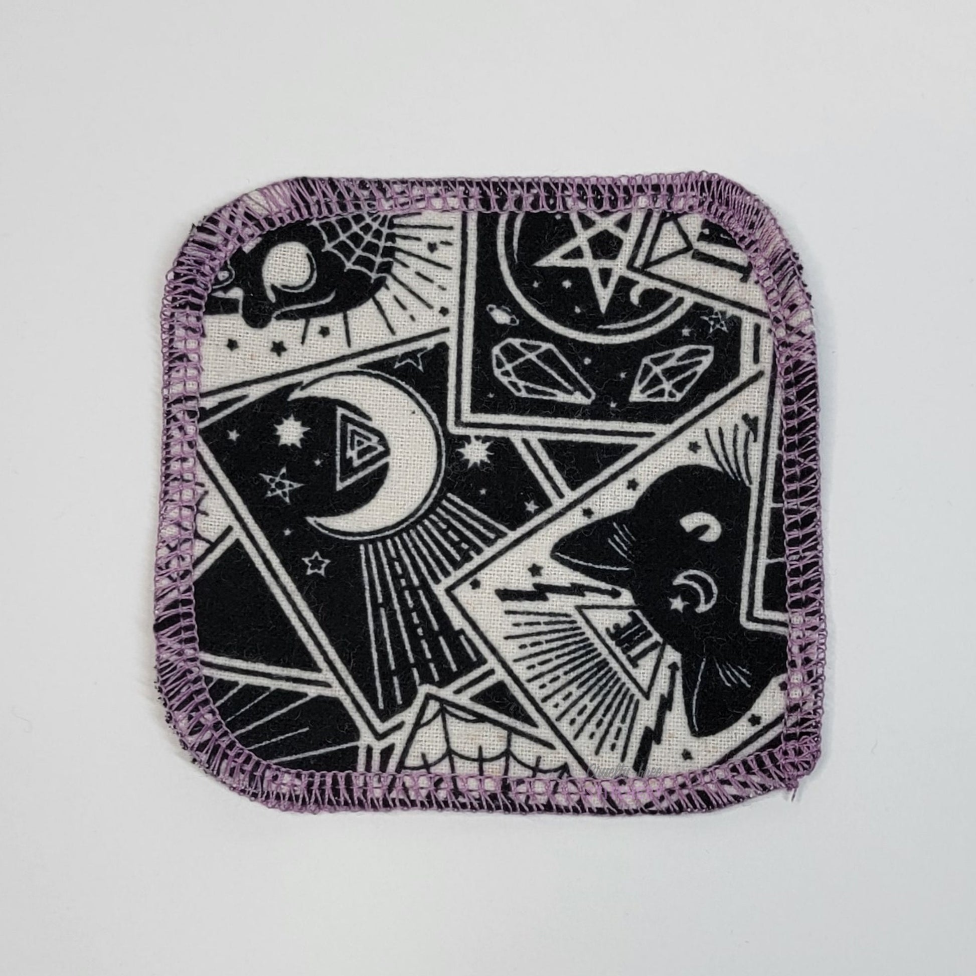 The front of one reusable cotton round in the tarot cards print. 