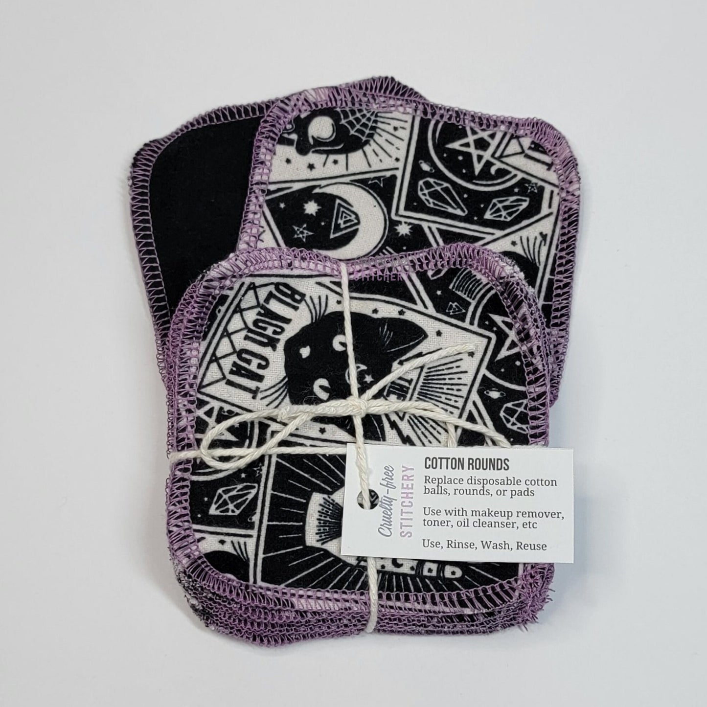 Tarot cards print reusable cotton rounds, a bundled pack tied with cotton string and a small paper tag, on top of one face-up and one face-down to show the different sides.