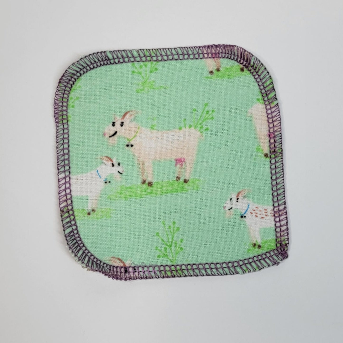 The front of one goats print reusable cotton round. 