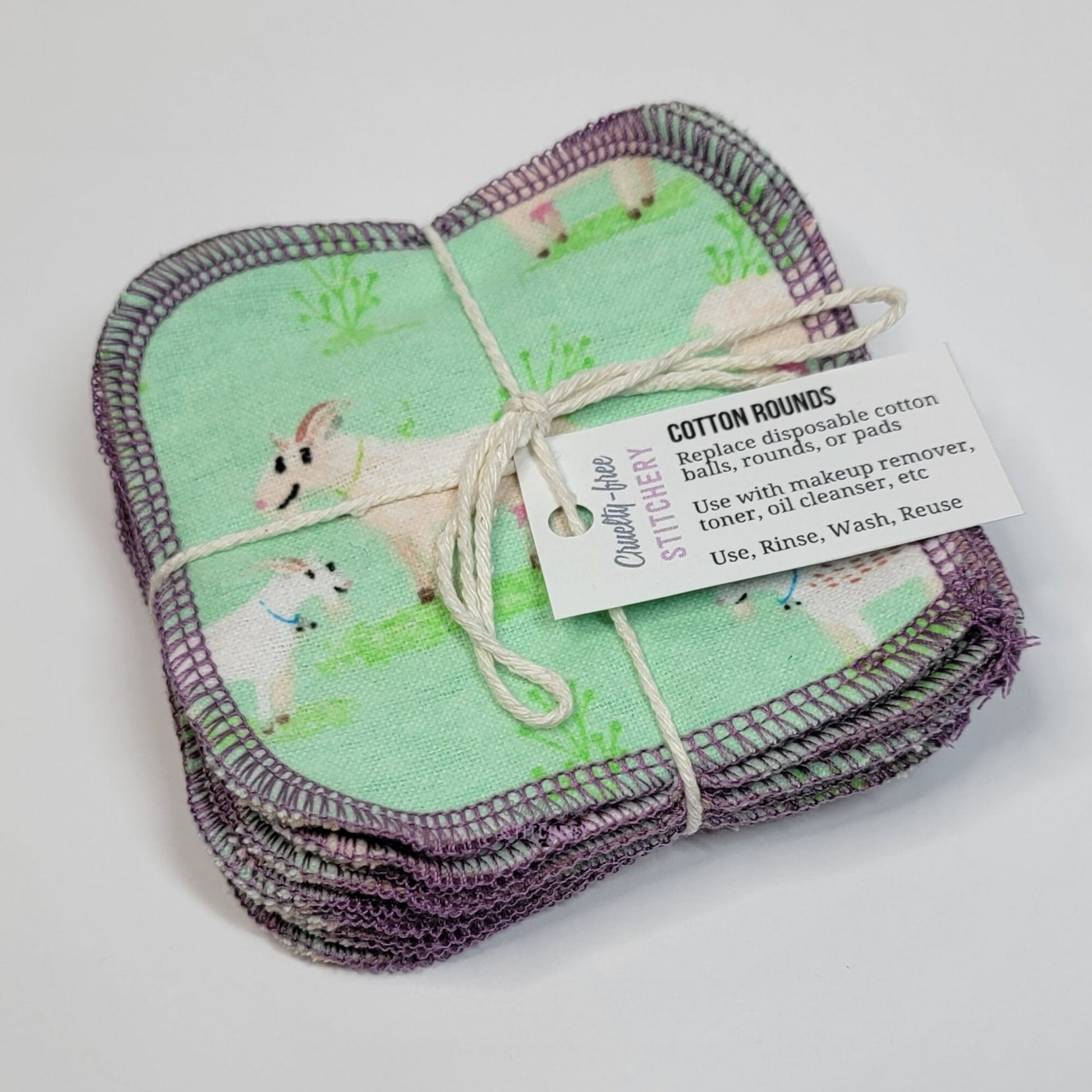 A bundled pack of the goats print reusable cotton rounds. They are tied with a thin white string like a gift, and have a small paper tag.