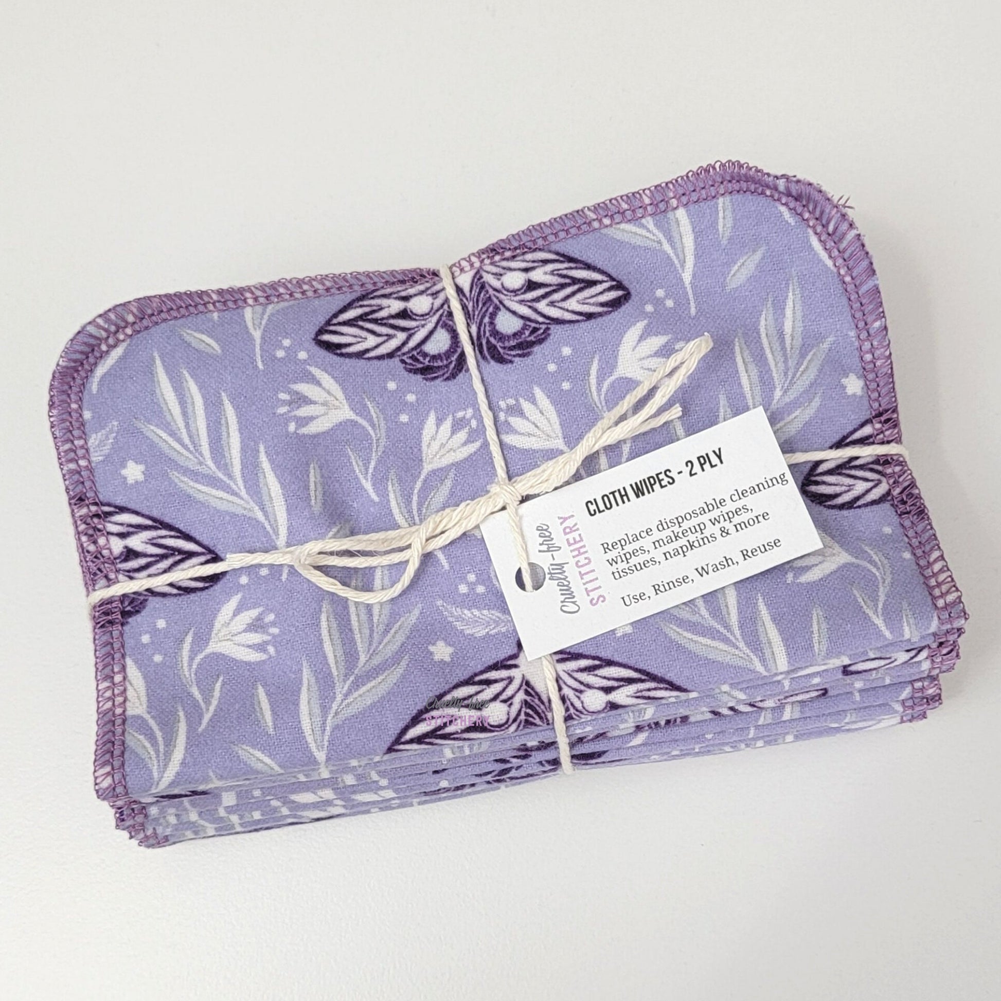 A folded and bundled pack of purple moths cloth wipes, tied with string and a small white tag.