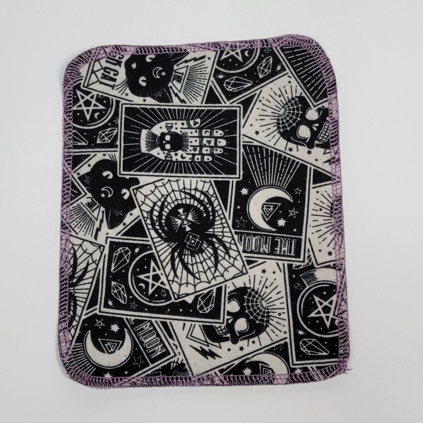 One tarot cards cloth wipe to show the full print with the various tarot cards, such as the moon, a skull, spider, black cat, etc.